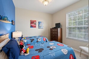 Ein Schlafzimmer mit zwei Betten, einem Schminktisch, einem Fernseher und Postern an der Wand.