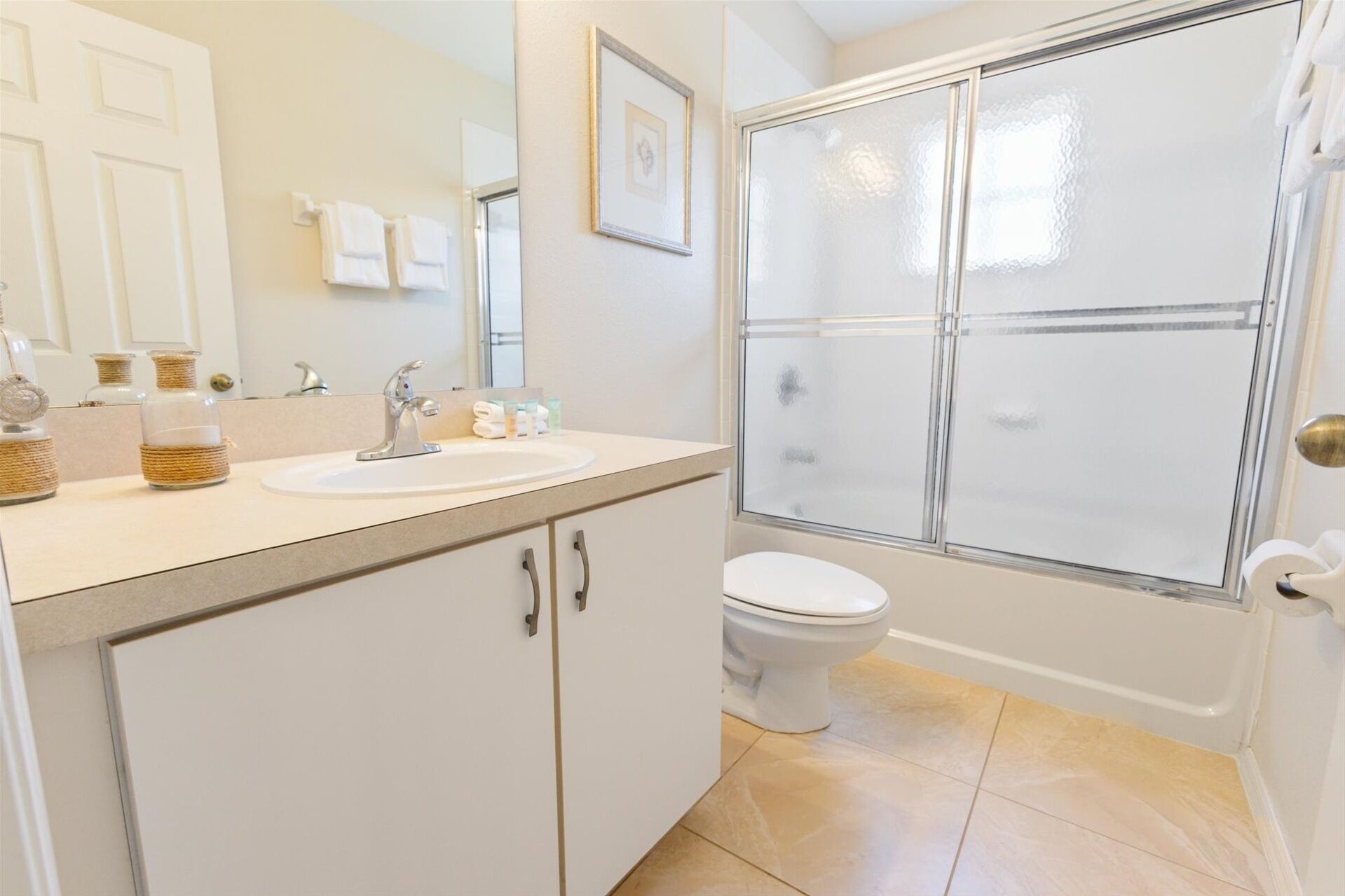 A bathroom with a sink, toilet, and glass shower enclosure.
