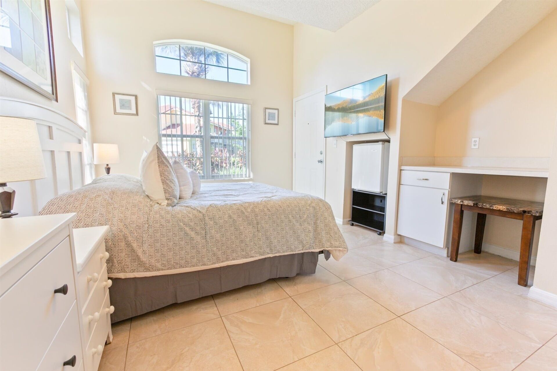 A bedroom with a bed, a desk, and a TV.