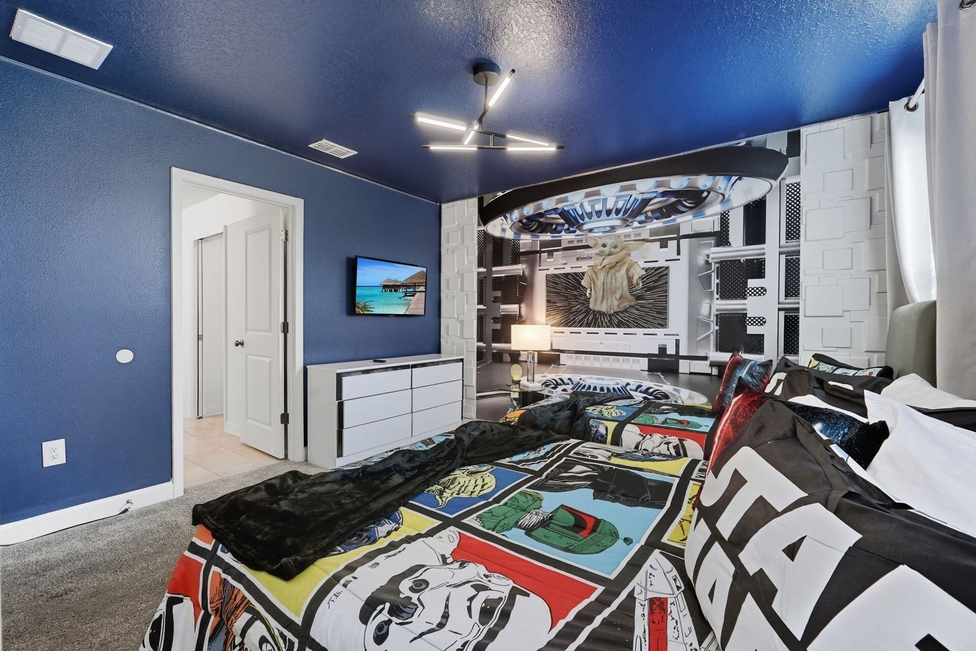 Una camera da letto con un letto, una TV, un armadio e una ventola a soffitto.