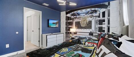 Una camera da letto con un letto, una TV, un armadio e una ventola a soffitto.