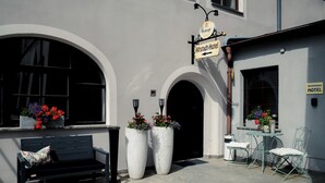 An outdoor seating area with a bench and chairs, large planters with flowers, and a sign for the Altstadt-Hotel. - Altstadt-Apartment (Freiberg)