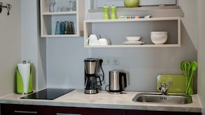 A modern kitchen with a countertop, a coffee maker, a kettle, and a sink. - Altstadt-Apartment (Freiberg)