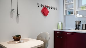 A modern kitchen with a white countertop, red cabinets, and a hanging rack with heart-shaped decorations. - Altstadt-Apartment (Freiberg)