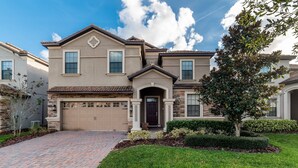 A two-story house with a garage, a front entrance, and a well-maintained lawn. - Championsgate Resort 9 Bedroom Private Pool Home 9 Home (Davenport)