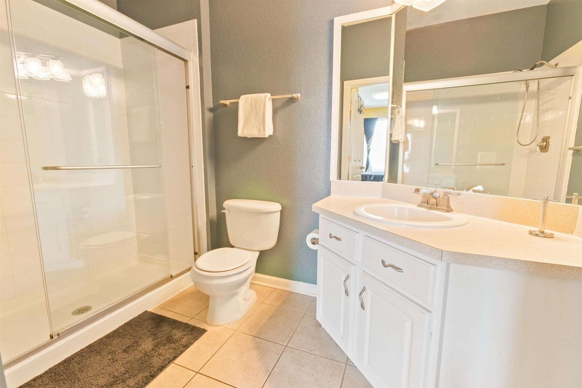 A bathroom with a glass-enclosed shower, a toilet, a sink, and a mirror.