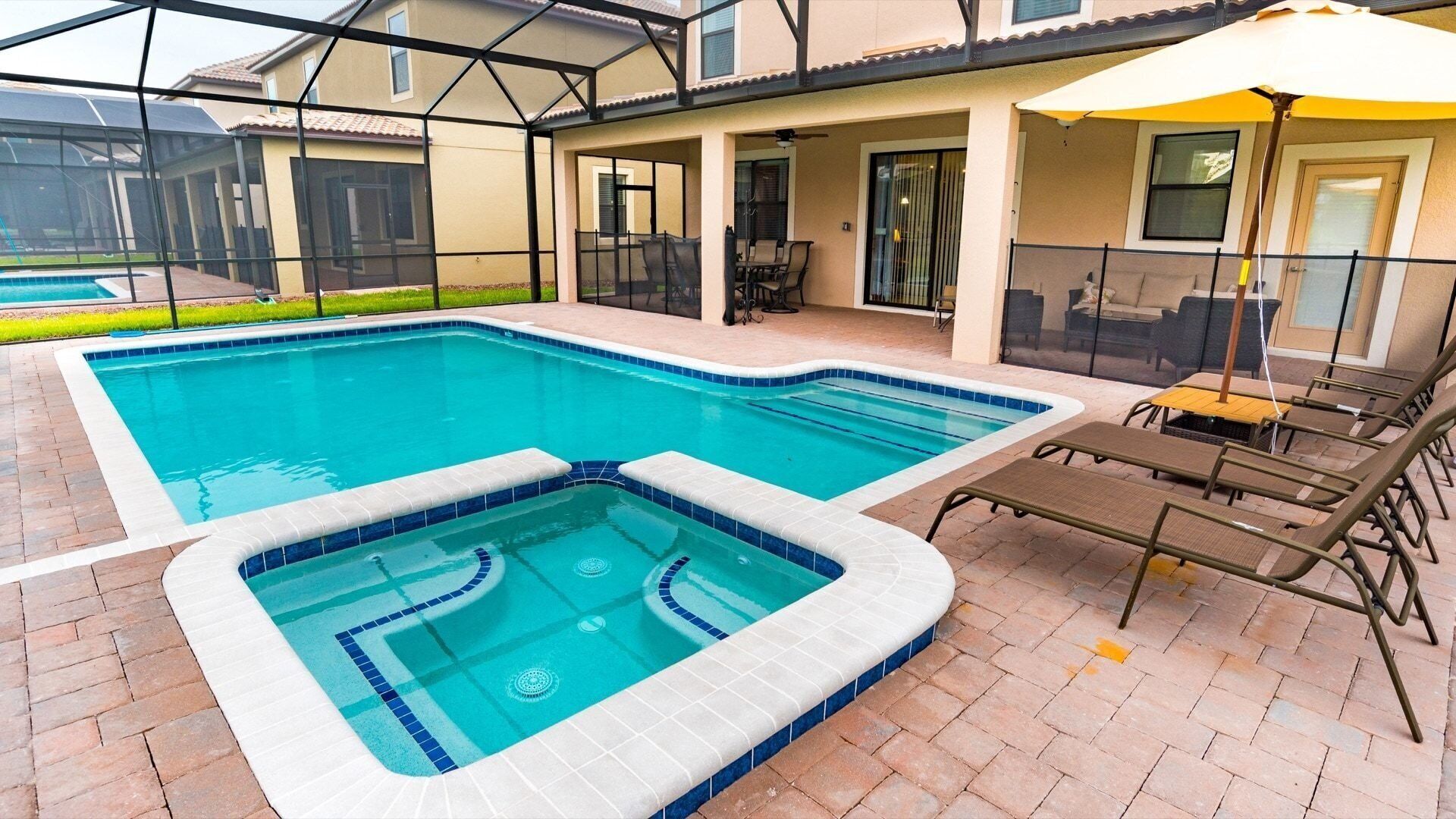 Ein Pool mit Whirlpool, Sitzgelegenheiten im Freien und einer überdachten Terrasse.