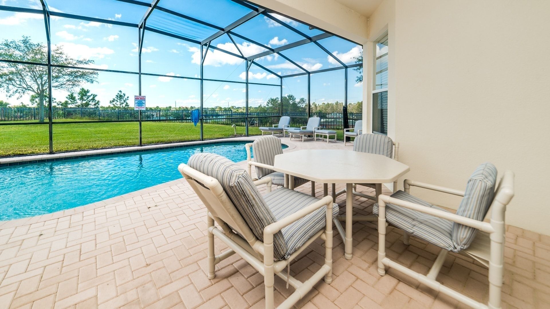 A covered patio with a pool, outdoor furniture, and a view of the surrounding landscape.