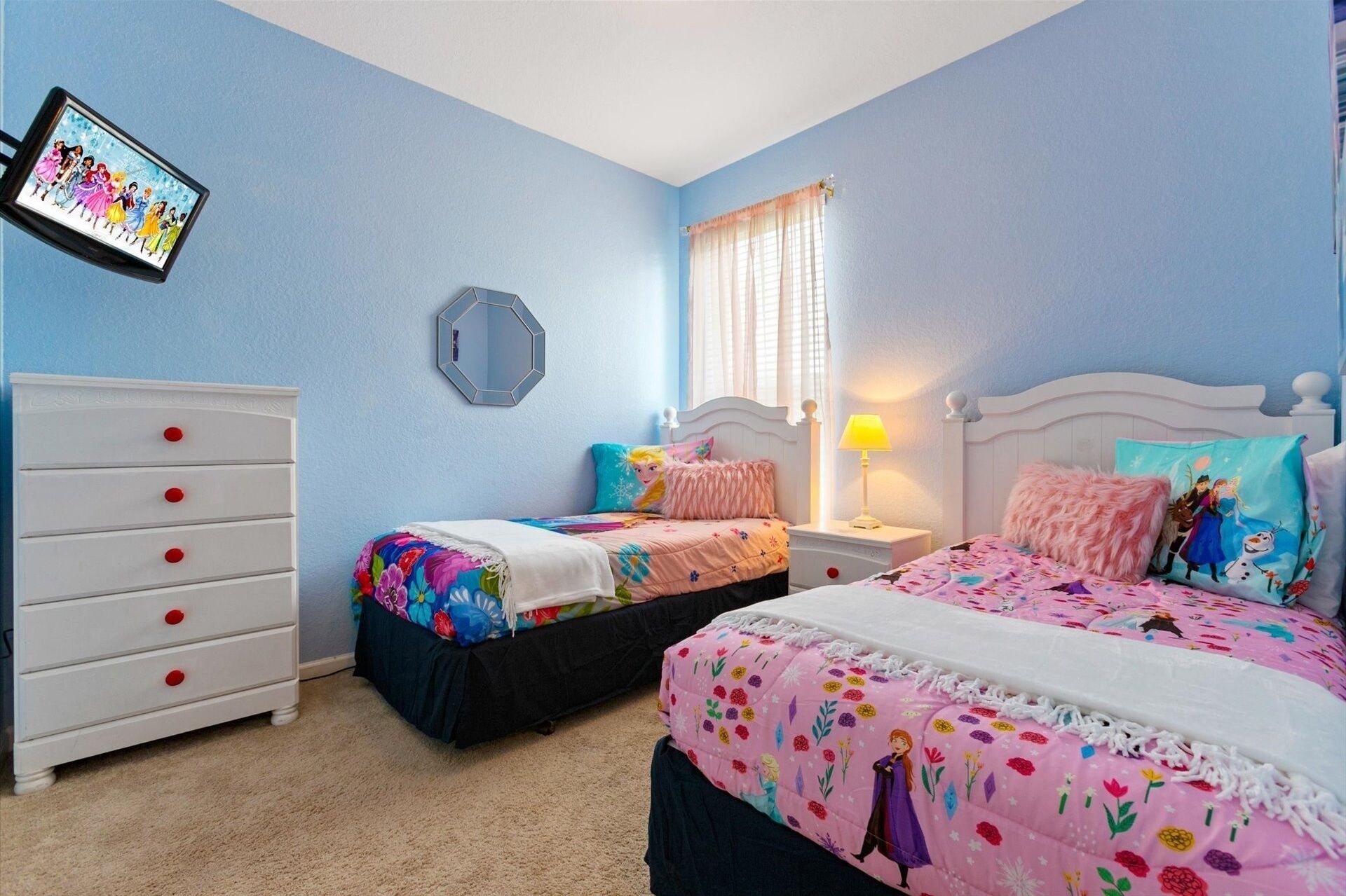 Quarto com duas camas, uma cômoda, um espelho e um quadro na parede.