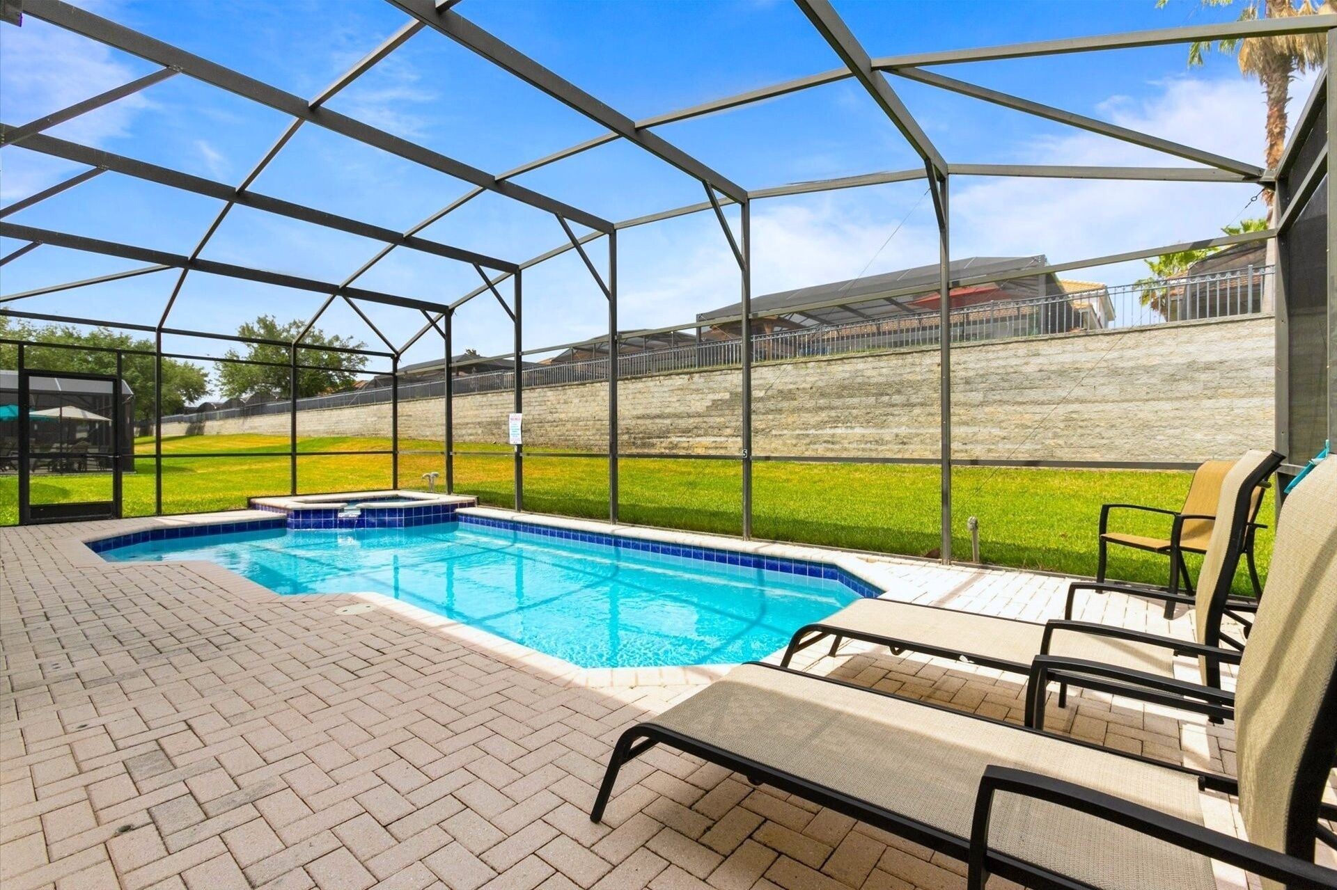 Une piscine couverte avec des chaises longues et une terrasse en briques.
