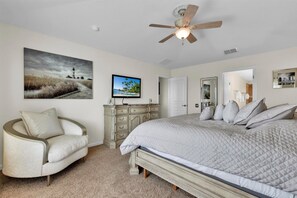 A bedroom with a large bed, a ceiling fan, a dresser, a chair, and artwork on the walls. - Windsor Hills Resort 6 Bedroom Private Pool+Spa Home 6 Home (Kissimmee)