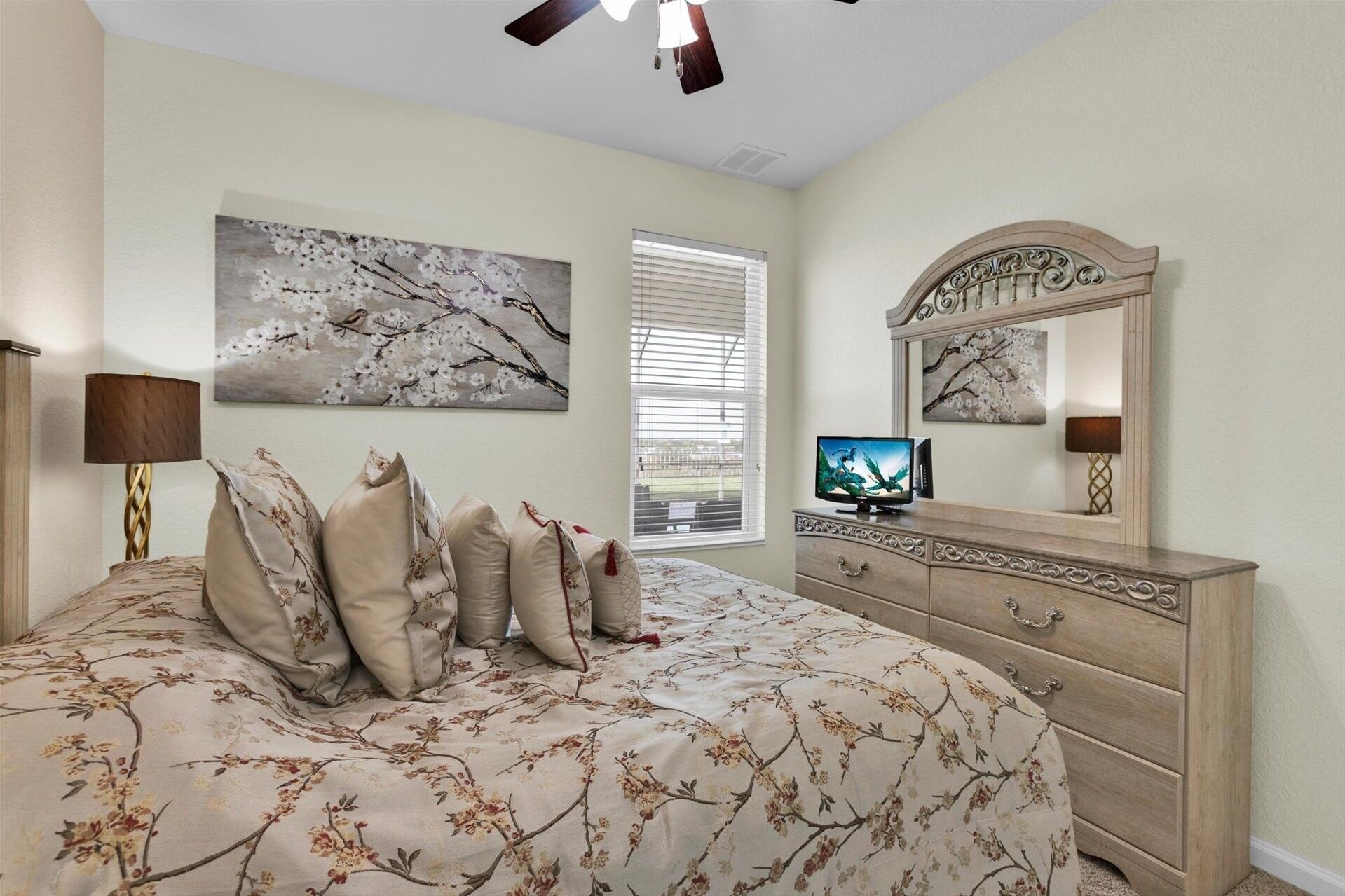 A bedroom with a bed, a dresser, a television, and two wall-mounted paintings.