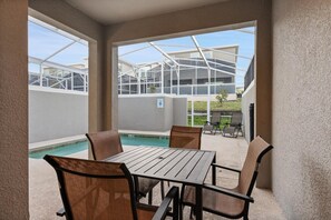 Ein überdachter Außenbereich mit Pool, Tisch und Stühlen.