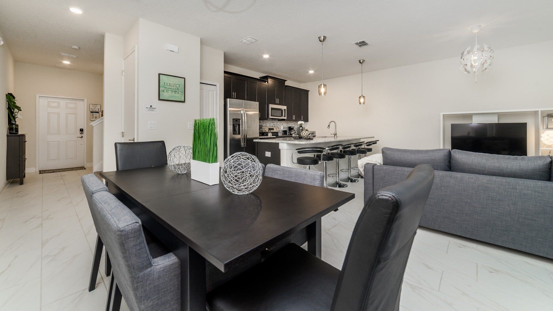 A modern kitchen with dark cabinets, a stainless steel refrigerator, and a microwave.
