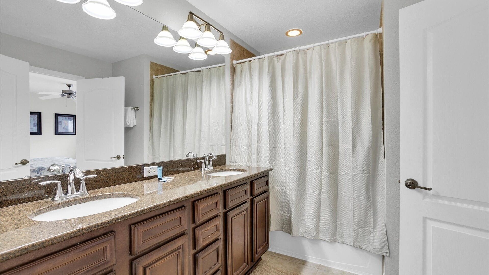Une salle de bain avec deux lavabos, un grand miroir et un rideau de douche.