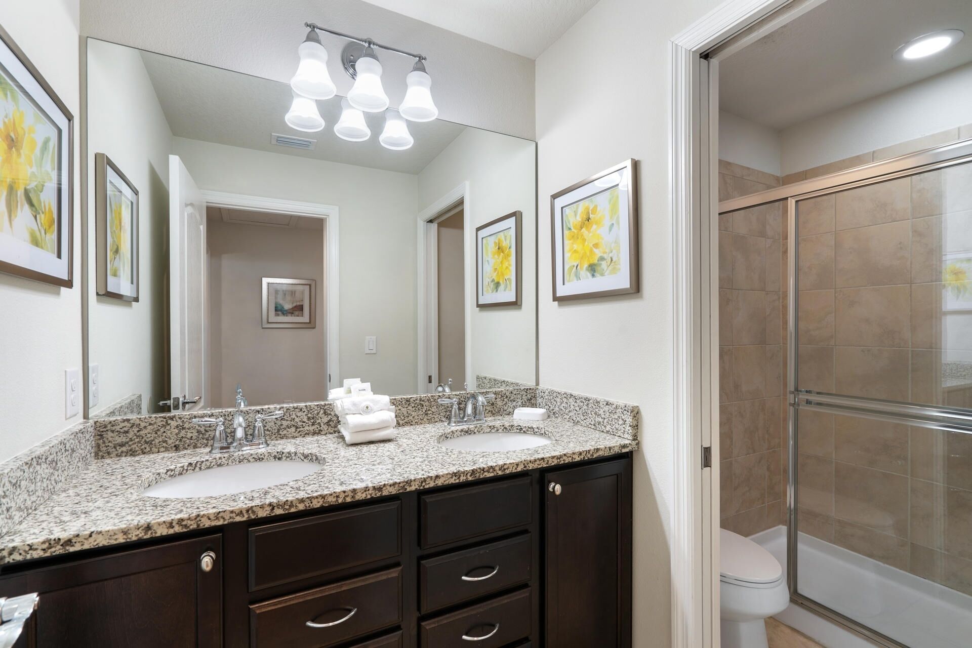 A bathroom with a double sink vanity, a large mirror, and a glass shower enclosure.