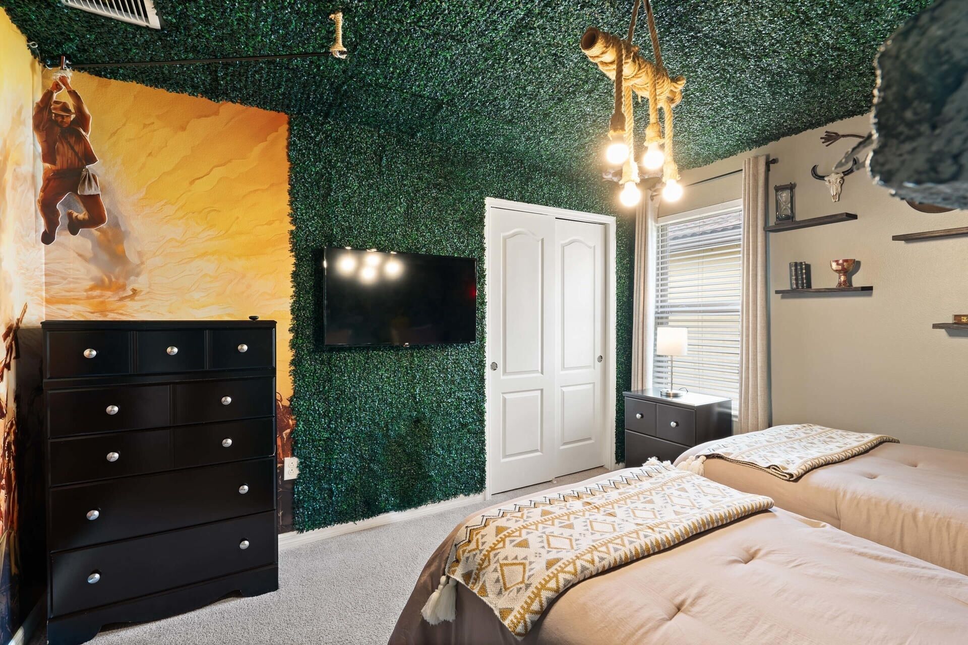 A bedroom with a green wall, a TV, a white door, and two beds.