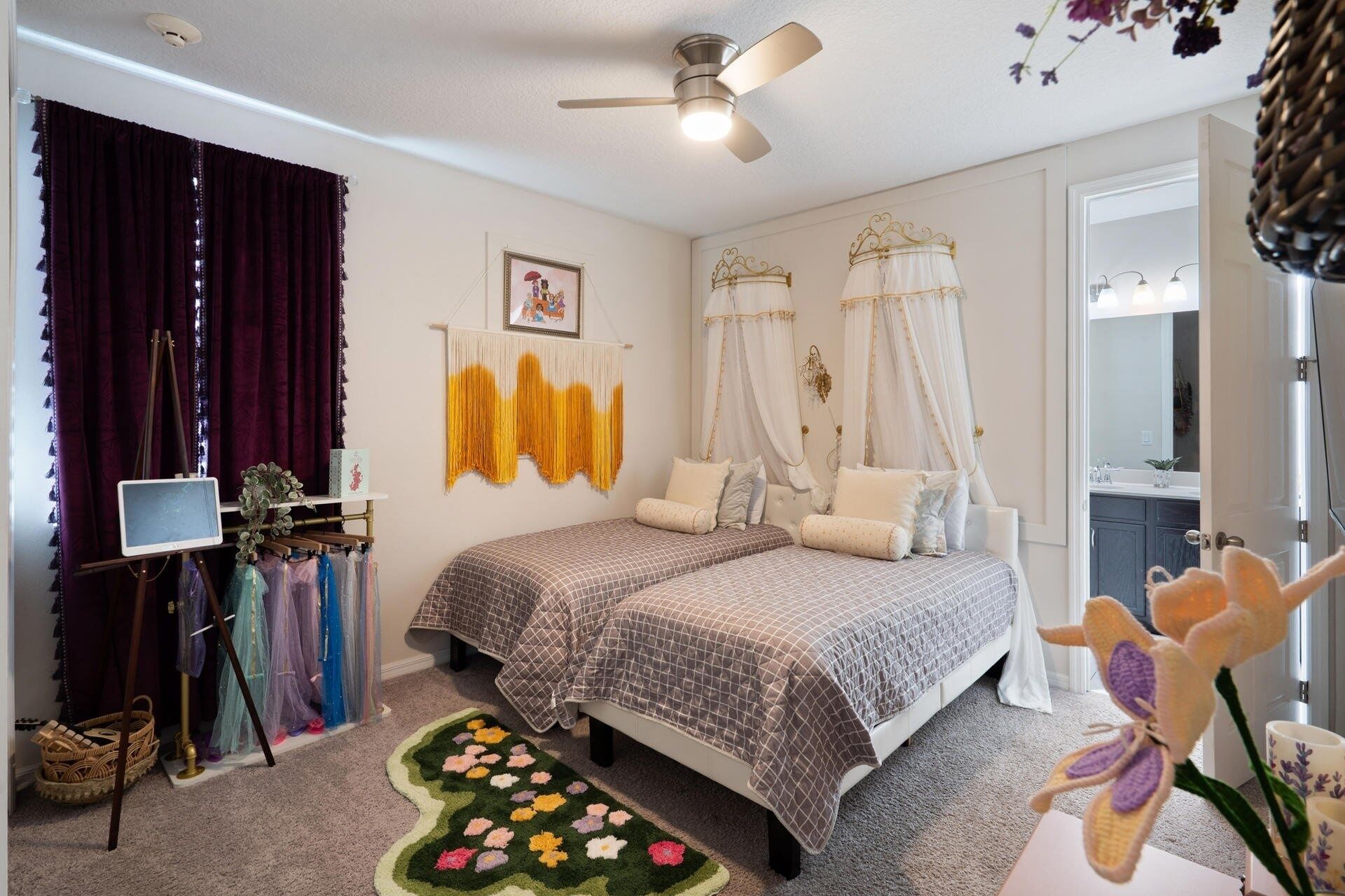 A bedroom with two beds, a ceiling fan, a large mirror, and a floral rug.