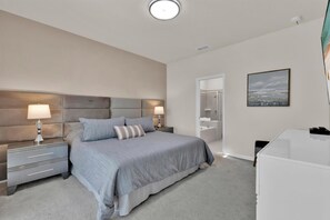 Quarto moderno com uma cama grande, duas mesas de cabeceira com luminárias, um closet espaçoso e um banheiro com chuveiro e pia.