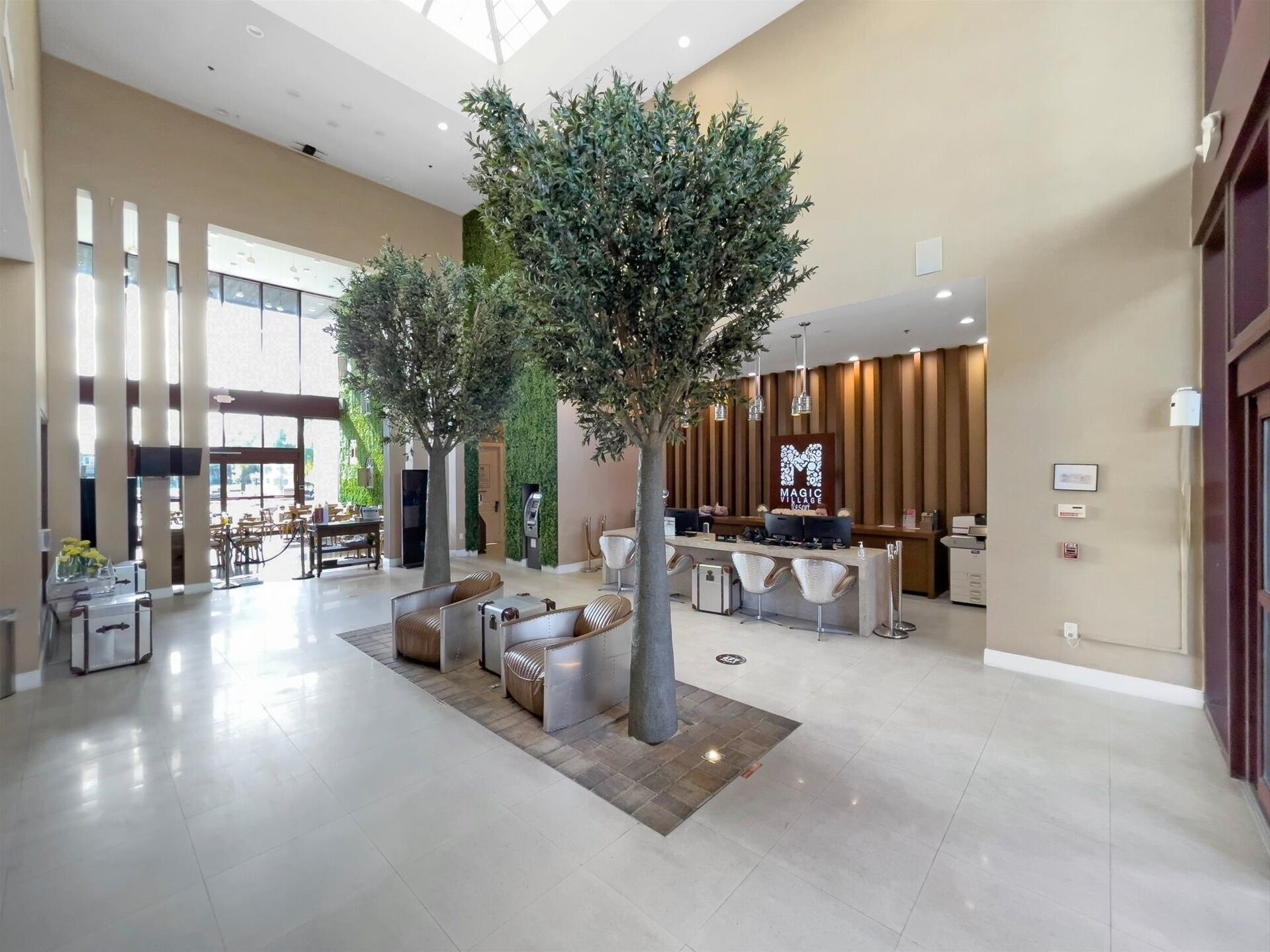 A spacious lobby with a reception desk, seating area, and a large tree.