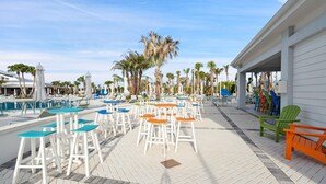 A poolside area with multiple lounge chairs and tables, a pool, and palm trees. - Windsor Cay Resort 5 Bedroom Townhome with Pool 5 Townhouse (Clermont)