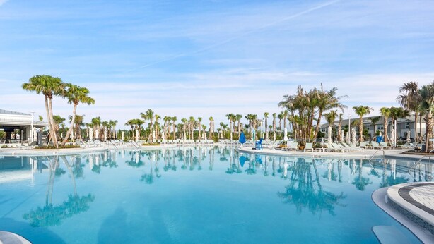 A large, clear swimming pool surrounded by palm trees and lounge chairs. - Windsor Cay Resort 5 Bedroom Townhome with Pool 5 Townhouse (Clermont)