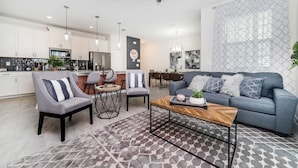 A modern living room with a grey sofa, two armchairs, a coffee table, and a dining area with a table and chairs. - Storey Lake Resort 4 Bedroom Townhome Pet Friendly 4 Townhouse (Kissimmee)