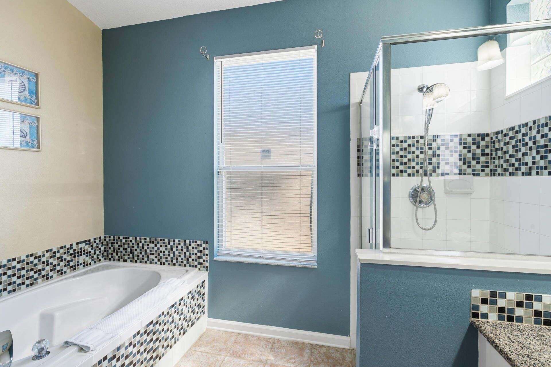 A bathroom with a bathtub, a shower, and a window with blinds.