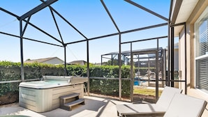 Un espacio al aire libre techado con un jacuzzi, sillones de descanso y una piscina.