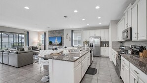 A modern kitchen with white cabinetry, granite countertops, and stainless steel appliances. - Solara Resort 9 Bedroom Private Pool Home 9 Home (Kissimmee)