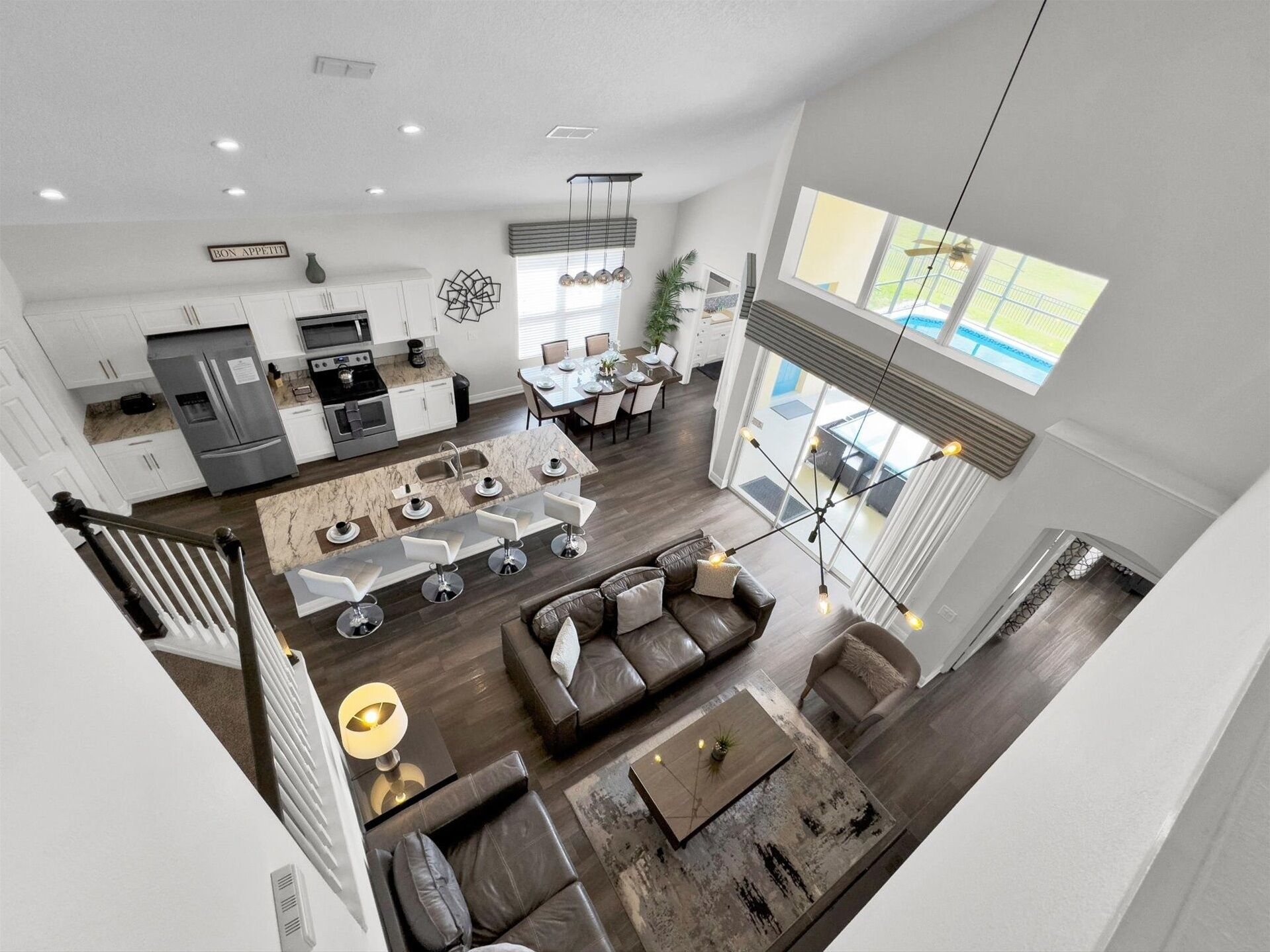 A modern open-plan living area with a kitchen, dining space, and a staircase leading to an upper level.