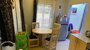 A compact kitchen with a dining table and chairs, a refrigerator, and a sink.