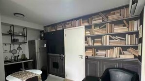 A compact living space with a kitchenette, dining area, and a bookshelf. - Lapa apartment swimming pool (Rio de Janeiro)