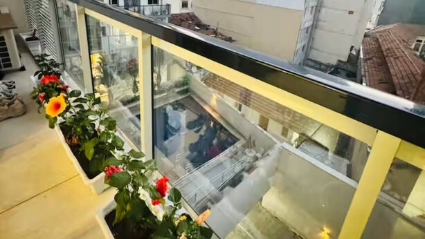 A balcony with a glass railing, potted plants, and a view of surrounding buildings. - Lapa apartment swimming pool (Rio de Janeiro)