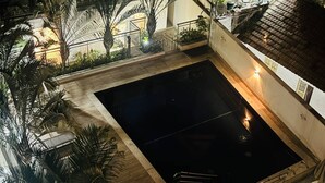 A rooftop pool area with surrounding palm trees and a staircase leading to an upper level. - Lapa apartment swimming pool (Rio de Janeiro)