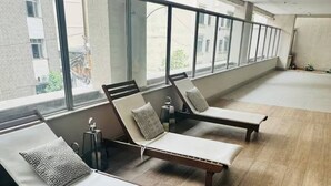 A spacious room with three sun loungers aligned against a wall with large windows, allowing natural light to fill the space. - Lapa apartment swimming pool (Rio de Janeiro)