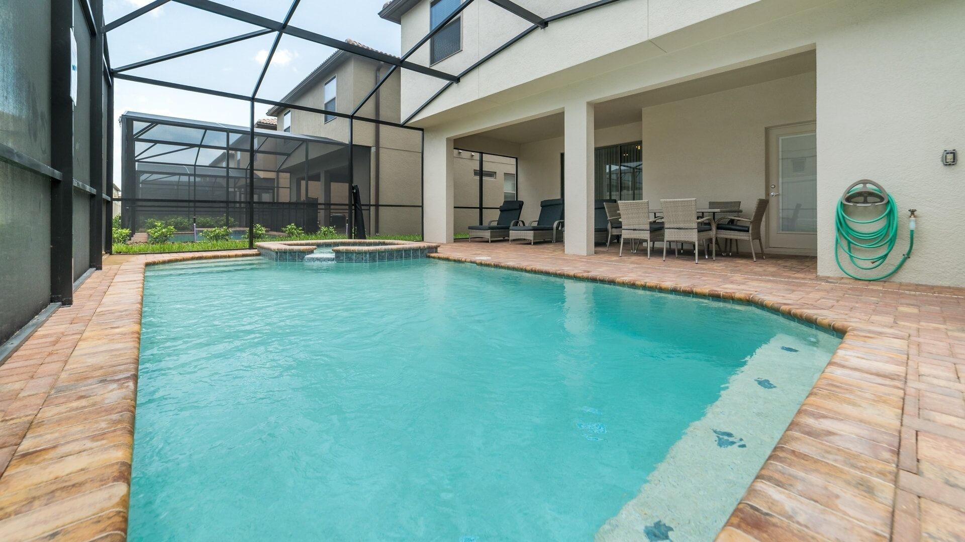 A swimming pool with a glass ceiling, surrounded by a patio area with outdoor furniture.