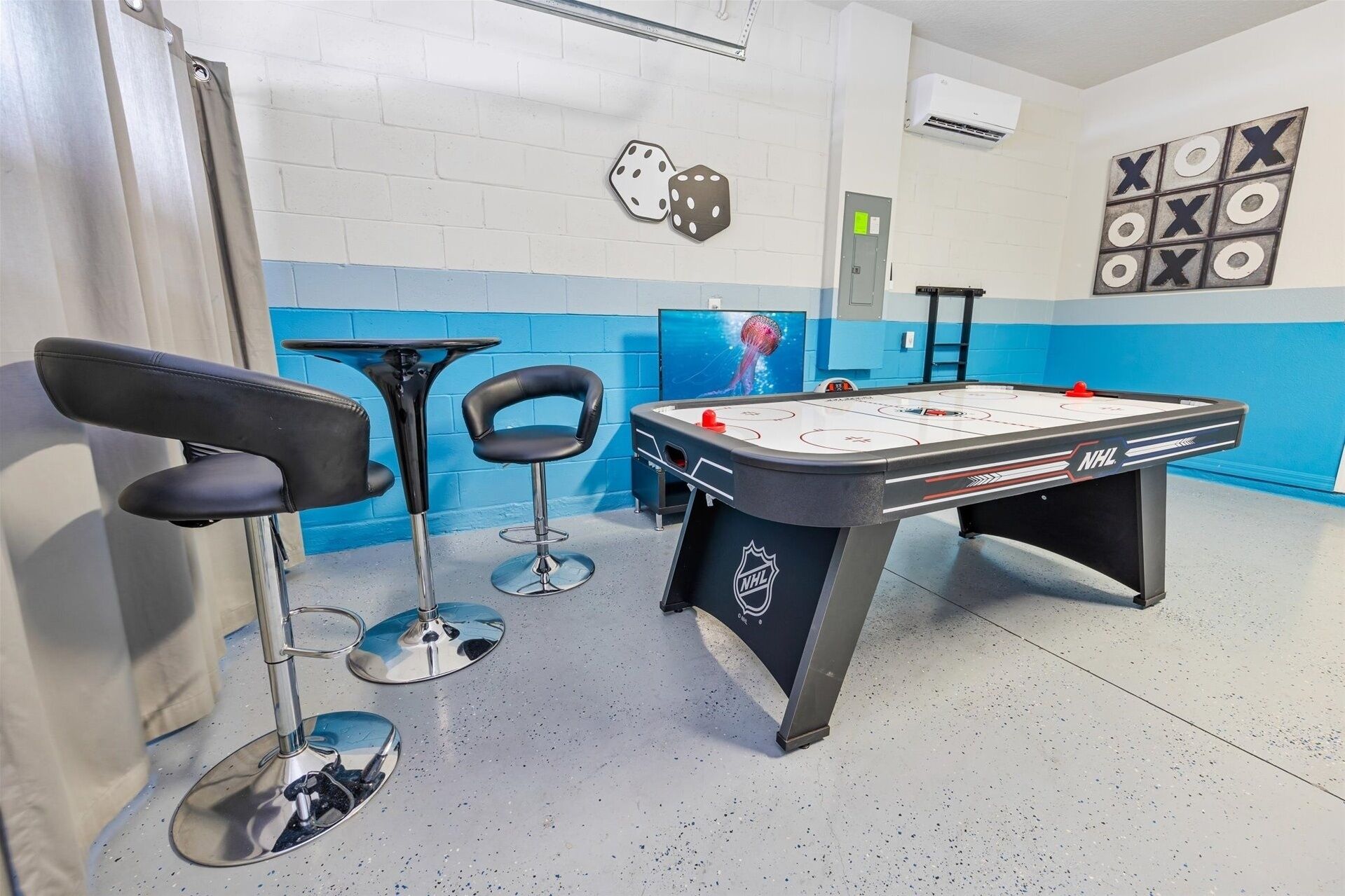 A room with a foosball table, two bar stools, and a TV screen displaying a jellyfish.