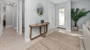 A modern living room with a wooden console table, a round mirror, and a potted plant. - 🌊 Waterfront Escape | Canal-Front Retreat w/ Private Pool (Naples)