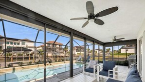 A covered outdoor area with a pool, seating, and a view of the surrounding neighborhood. - 🌊 Waterfront Escape | Canal-Front Retreat w/ Private Pool (Naples)