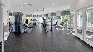 Uma academia moderna com diversos equipamentos de exercício, janelas amplas e um espaço limpo e arejado.