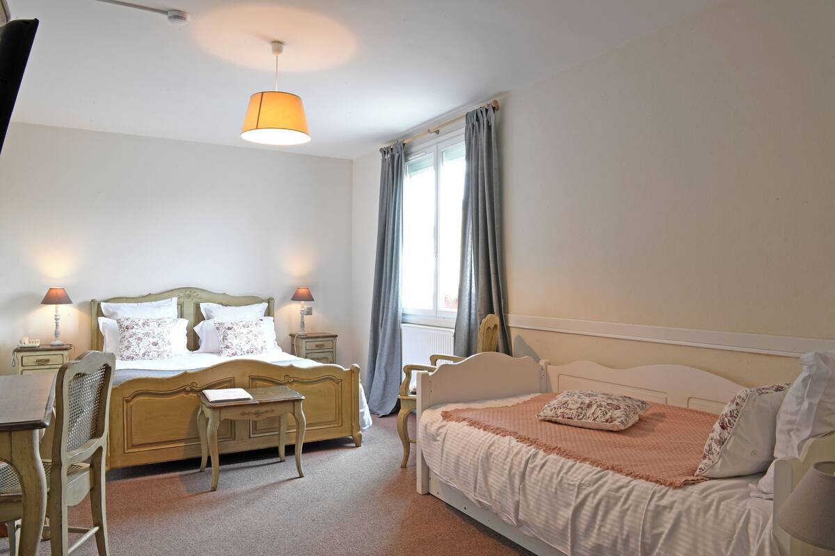 A bedroom with a double bed, a single bed, a desk, and a chair.