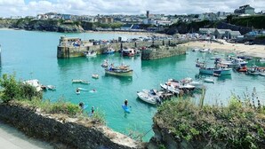 A coastal marina with boats docked, a sandy beach, and a rocky shoreline. - Beachfront Luxury Home with Hot Tub, 9 beds, Cinema room, Sleeps 2 to 16 (Newquay)
