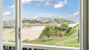 A coastal view with a beach, a hill with buildings, and a clear sky. - Beachfront Luxury Home with Hot Tub, 9 beds, Cinema room, Sleeps 2 to 16 (Newquay)
