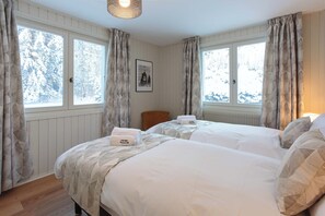 Een hotelkamer met twee bedden, een ingelijst schilderij aan de muur en ramen voorzien van gordijnen.