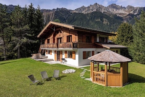 Een chalet met balkon, jacuzzi en een houten prieel.