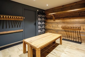 A wooden table in a room with a grey door and a wooden wall with a wine rack. - Chalet le Petit Tricouni, ski, Chamonix All Year (Chamonix)