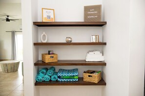 A bathroom with a wooden shelf holding towels, a decorative item, and a sign indicating WiFi and password. - On Island -  New 2BR/2BA Condo with Central A/C, Convenient to Cruz Bay, Ocean Views (St John)