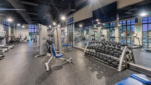 Un gimnasio con varios equipos de ejercicio, incluyendo cintas de correr, máquinas de pesas y mancuernas.