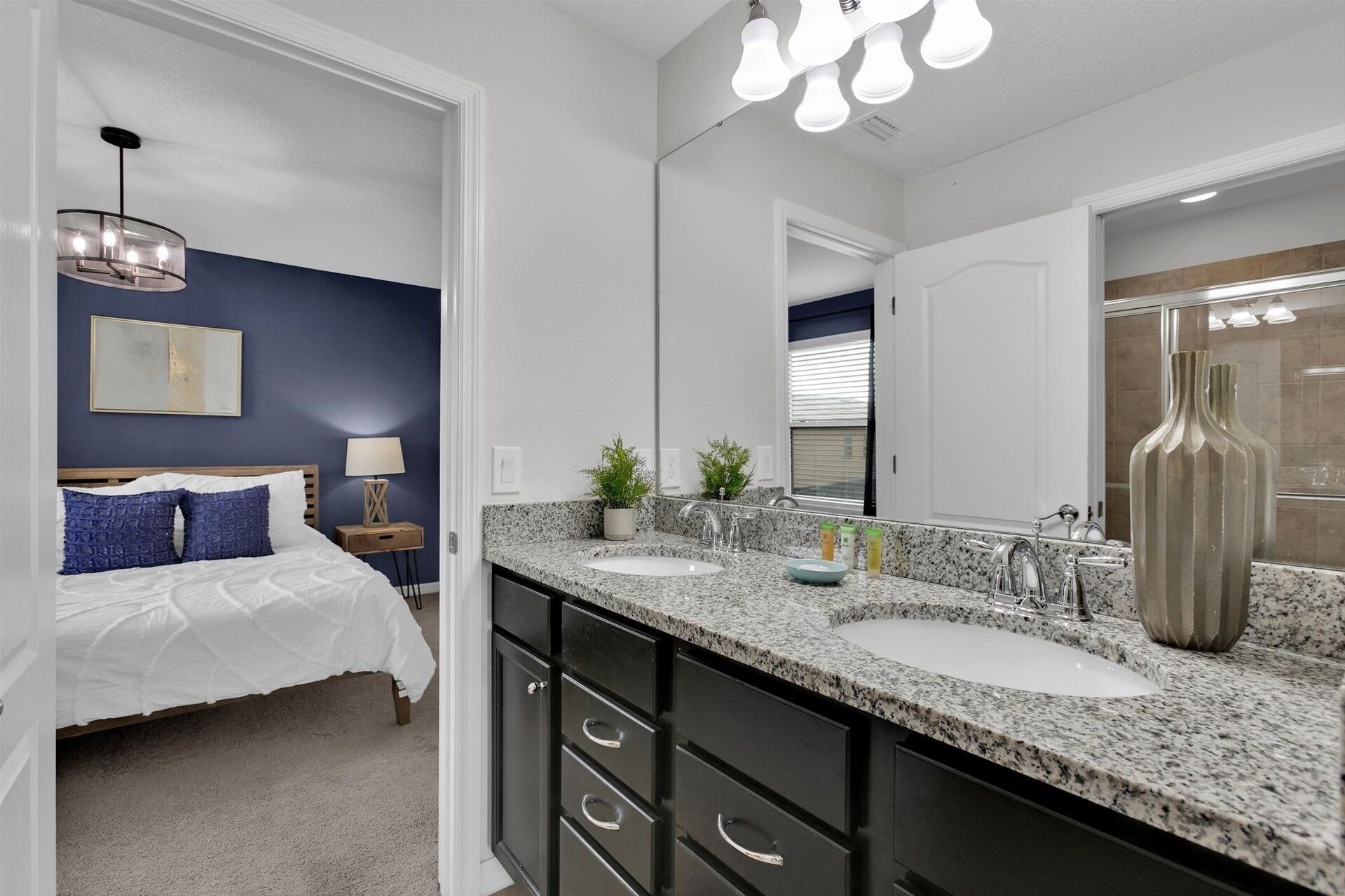 A modern bathroom with two sinks, a large mirror, and a shower area.